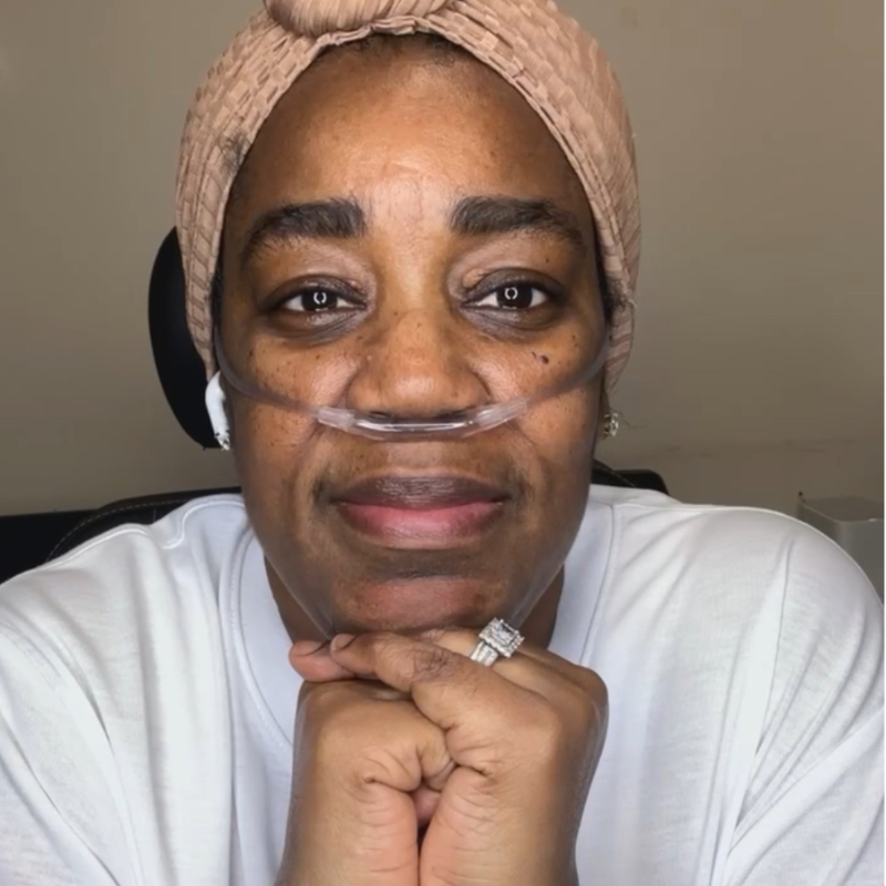 Katina, a lupus warrior and advocate, wearing a headwrap and oxygen tube